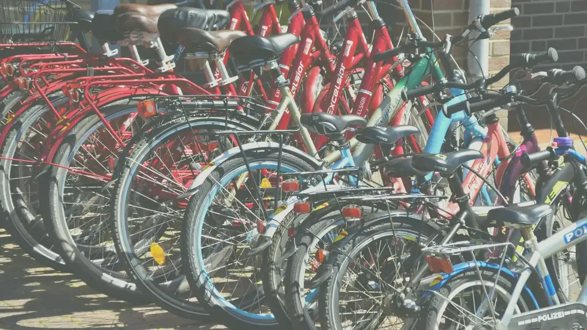 Rad med hyrcyklar i olika färger och storlekar parkerade i ett cykelställ